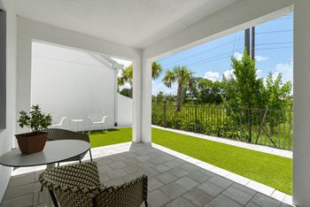 A patio with two chairs and a table and a lawn